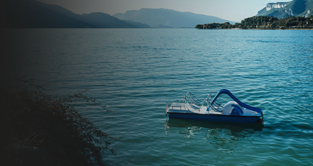 A blue pedal boat without occupants floats on a lake